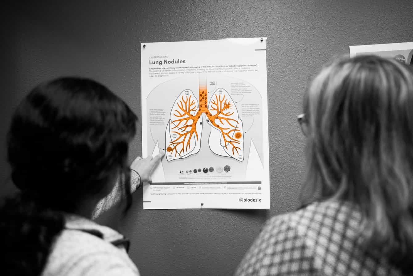 Two healthcare providers reviewing a Lung Nodules poster